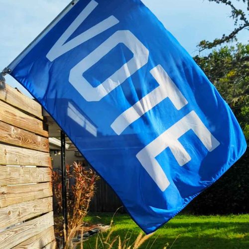 blue vote flag on a flagpole fence